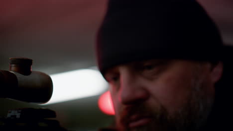 Man-using-binoculars-with-blue-lens.-Bearded-killer-aiming-with-assault-rifle