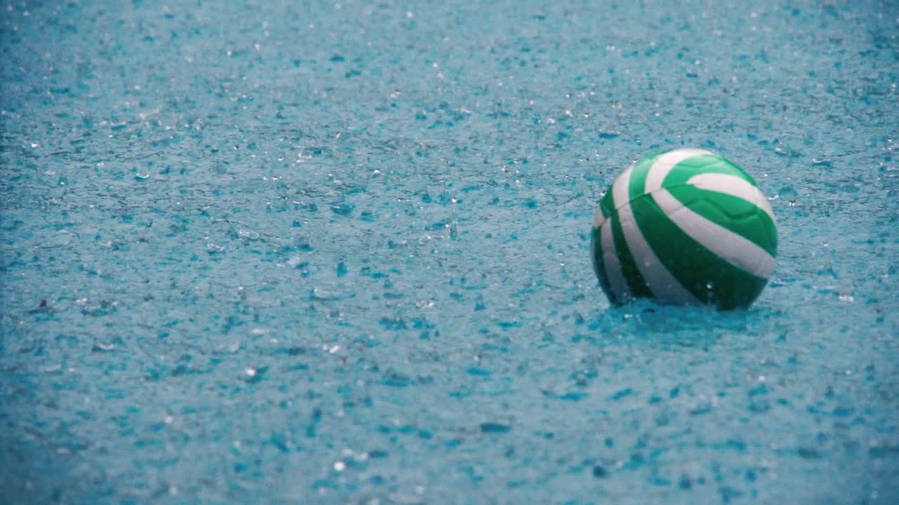 Rekaman gerak lambat menunjukkan bola voli mengapung naik turun di kolam renang pada hari hujan