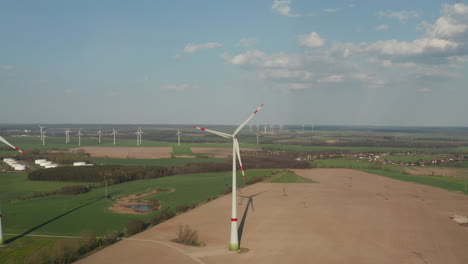 Rotating-rotor-with-striped-ends-of-blades.-Aerial-view-of-wind-turbines-in-flat-countryside.-Green-energy,-ecology-and-carbon-footprint-reduction-concept