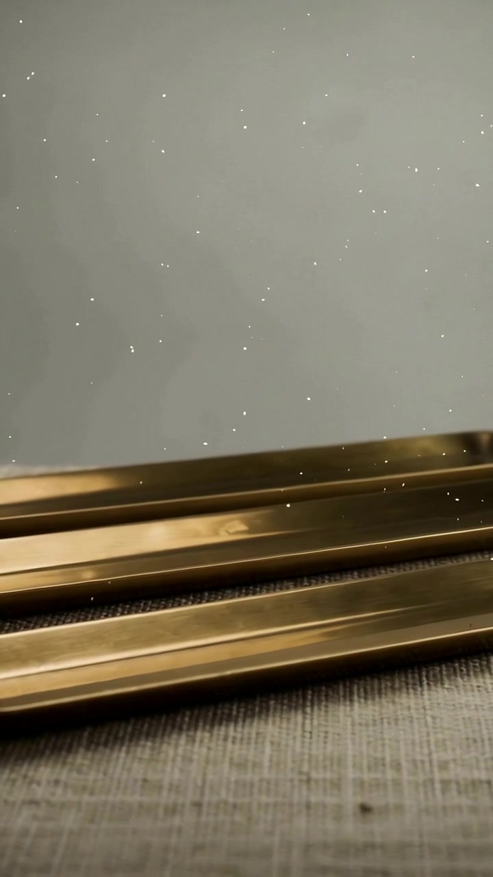 Video verticale: Luce mutevole che fa brillare due lingotti d'oro su una tovaglietta, con scintille fluttuanti