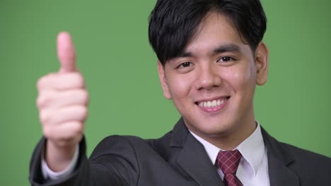 young handsome asian businessman giving thumbs up