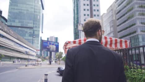 Attractive-and-Confident-Businessman-Walking-Near-Modern-Office-Building.
