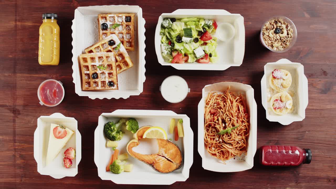 木製テーブルの上の多様な健康的なフードデリバリー料理（俯瞰）