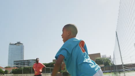 african american soccer kid in blue throwing the ball in a sunny day