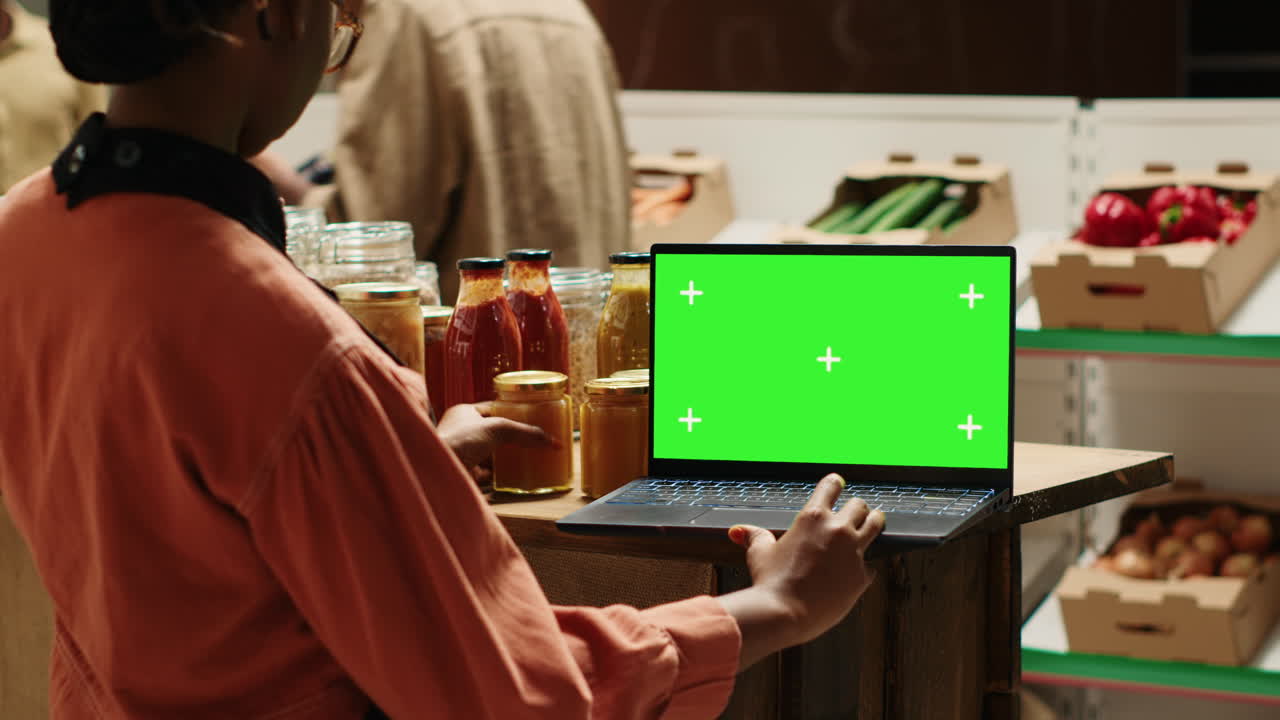 el vendedor mira la pantalla verde en la computadora portátil mientras prepara la mercancía
