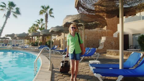 Steadicam-Shot-Of-Woman-With-Travel-Bag-Walking-On-Recreation-Area-Along-The-Pool