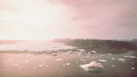 icebergs in lake below mountain and glacier