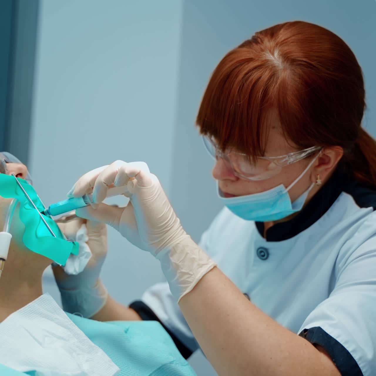 Dental specialist treats woman's teeth in clinic. Professional dentist makes injection into oral cavity to a patient in dental office.