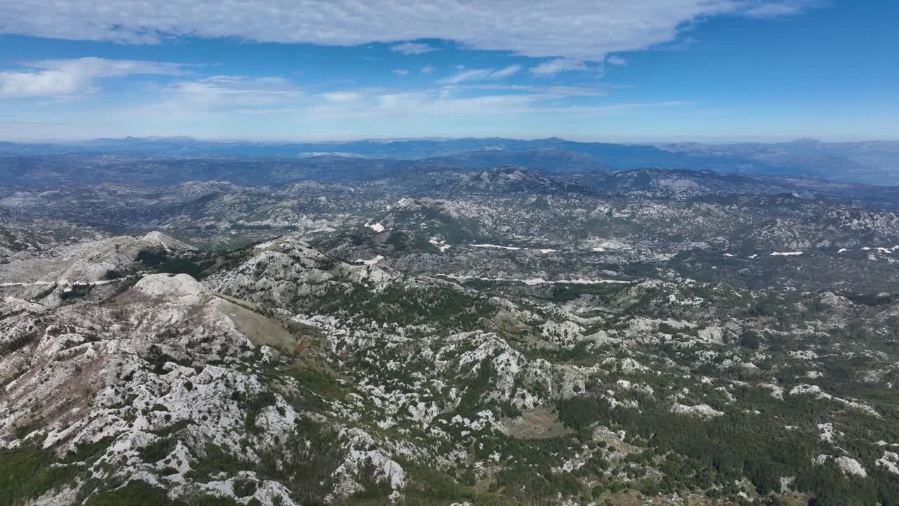 Witness the breathtaking beauty of Lovcen Mountain in Montenegro on a clear, sunny day with a vibrant blue sky. This stunning view captures the rugged peaks and expansive landscapes.