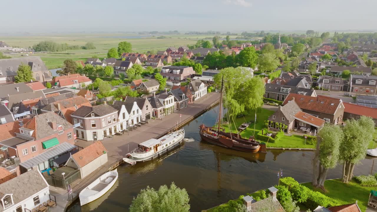 Aerial semi orbit around a Luxemotor boat sailing the canal in Heeg, Netherlands, surrounded by traditional Dutch houses