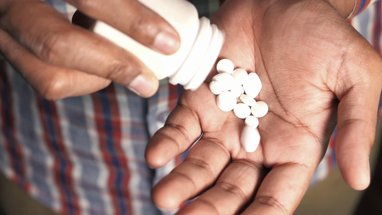 Person pouring pills from a bottle into their hands
