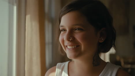 smiling young woman bathed in natural light by a window