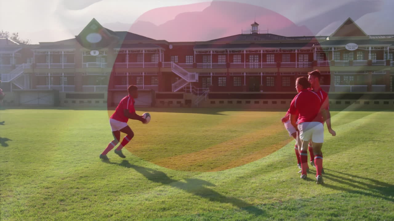Practicing rugby, players in red uniforms on grassy field near school building