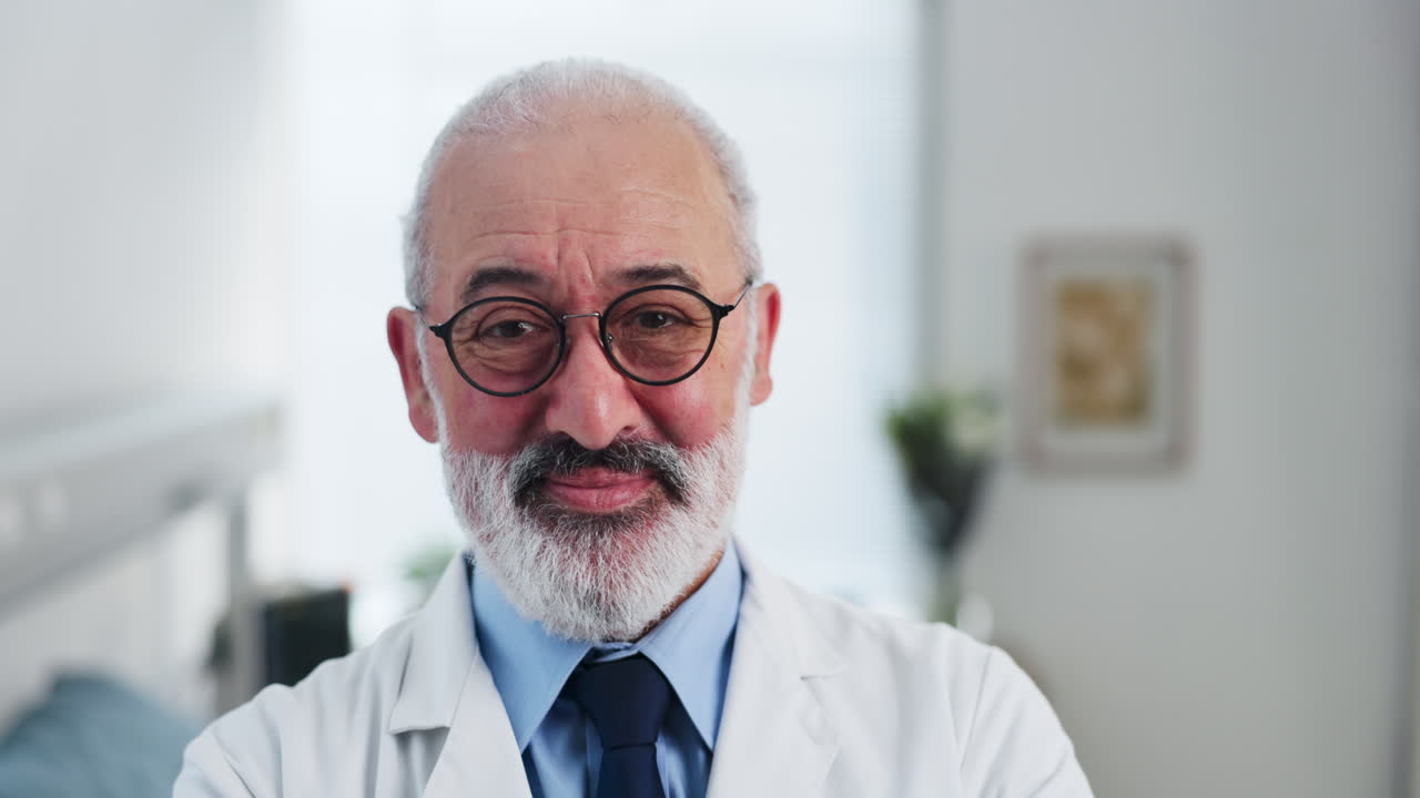 Médico Sênior Sorridente Olhando para a Câmera em Consultório Médico.