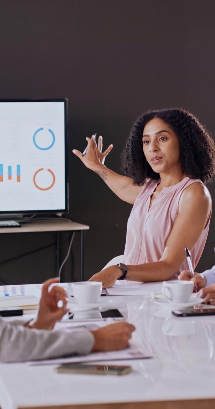 Imprenditrice che presenta grafici di dati ai colleghi in una riunione
