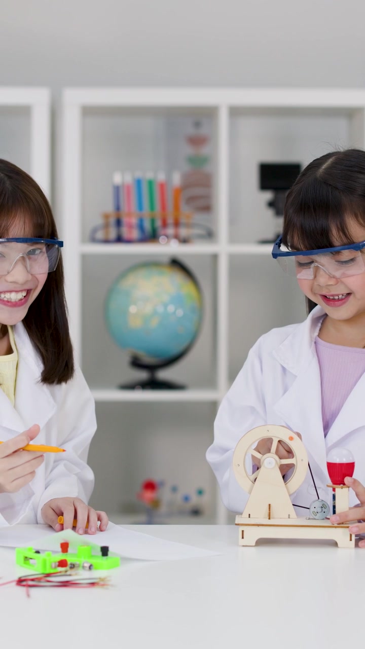 Two students in safety goggles celebrate a successful laboratory experiment with a joyful high five.