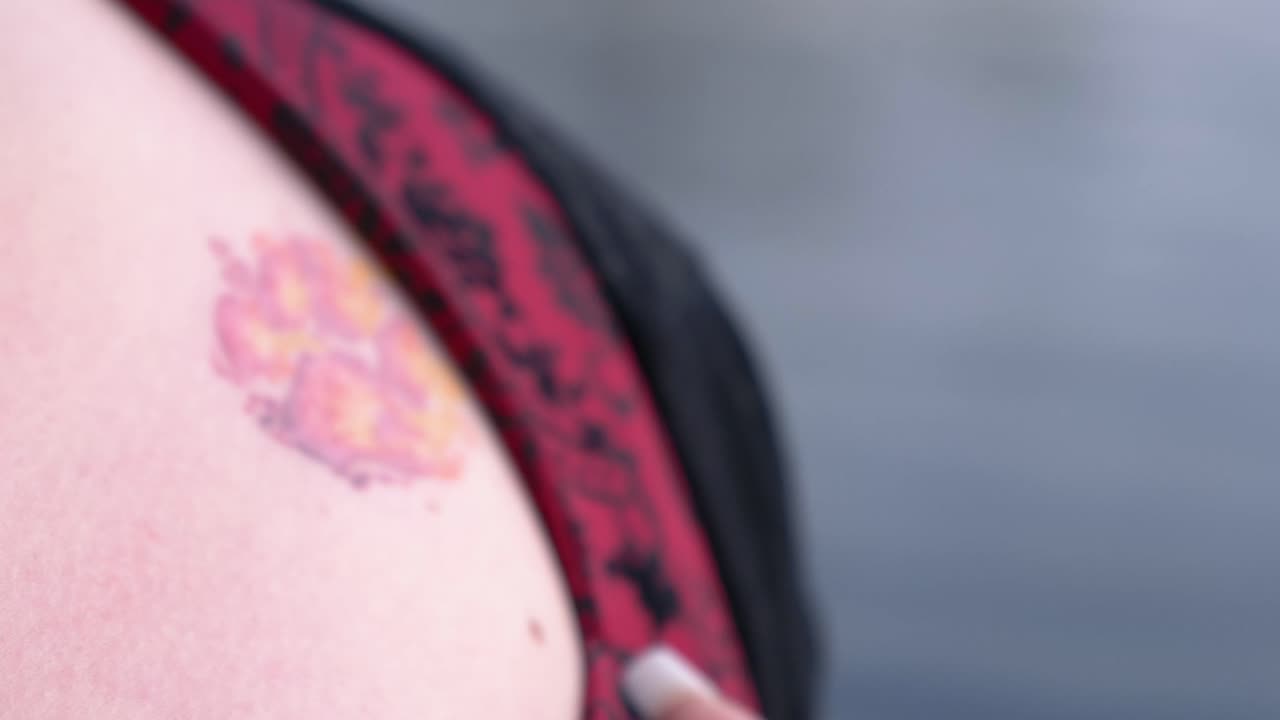 Slow motion close Up of a colored dog paw tattooed on a girl skin and dress with floral pattern. Smooth rotation of  the girl's shoulder towards the camera.