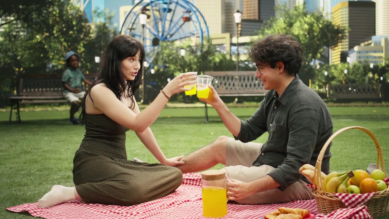 Young couple pouring orange juice into glasses before making cheerful toast