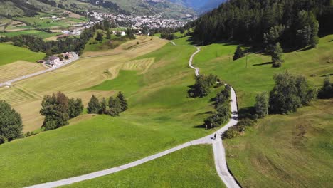 aerial: swiss valley and mountain biker following a path