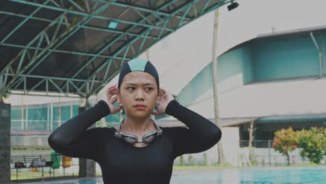 young woman puts on her swimming cap and prepares for a workout in the pool