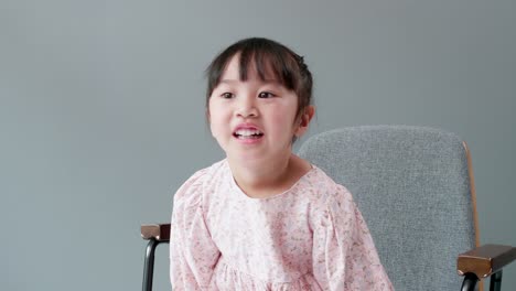 Cheerful-and-happy-Asian-children-3-Years-old-Sitting-in-a-chair-in-front-of-the-gray-background