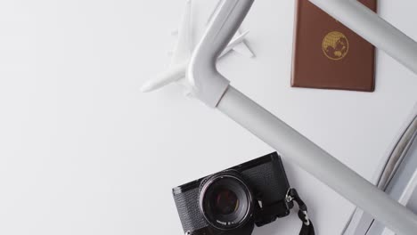 Close-up-of-passport,-suitcase,-plane-model-and-camera-with-copy-space-on-yellow-background