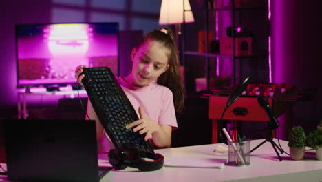 cute girl in studio using camera to review gaming keyboard, mouse and headphones