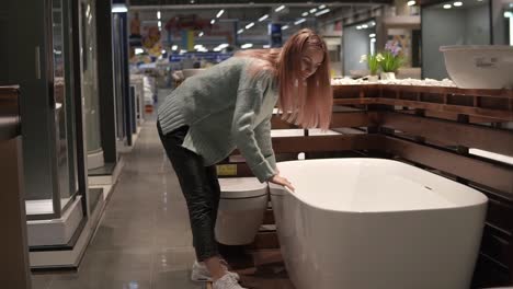 la mujer elige y toca un nuevo baño en una tienda de diseño de interiores