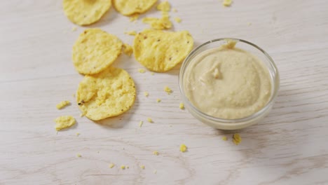 video of crisps and cheese dip on a wooden surface