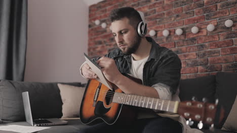 young musician man creating music, having ideas, taking notes at home