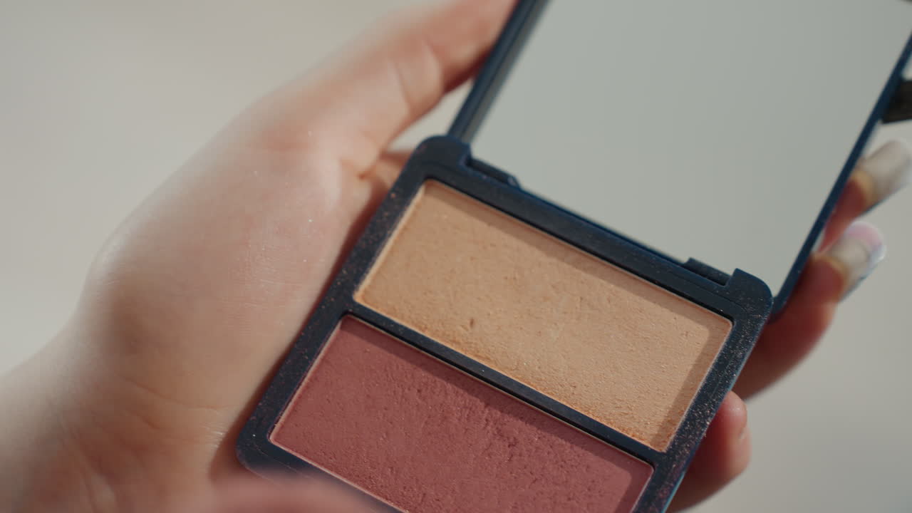 CloseUp Hand Holding Blush Palette, Brush Sweeping Coral Powder, Soft Bristles Pickup, Mirror Reflection, Polished Nails, Studio Lighting, Intimate Beauty Routine, Influencer Tutorial Vibe