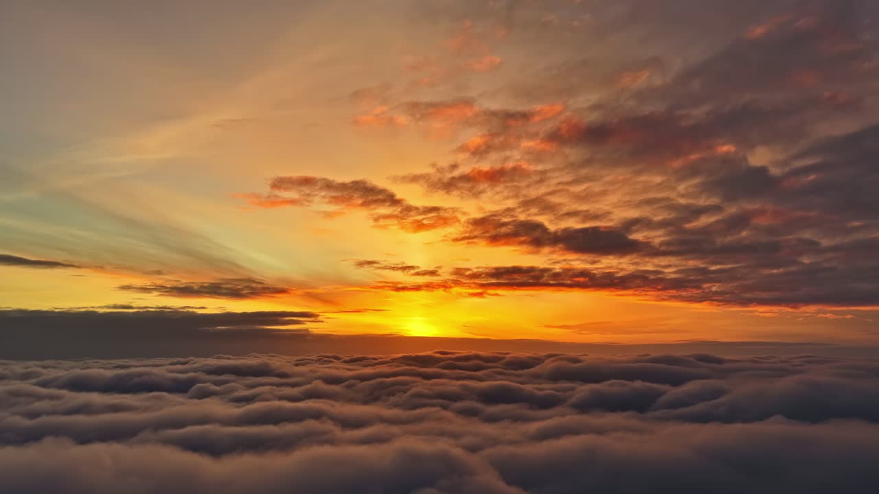 Cálido cielo celestial al amanecer sobre una gruesa capa de nubes que brilla en naranja a medida que el horizonte se ilumina al comenzar el día
