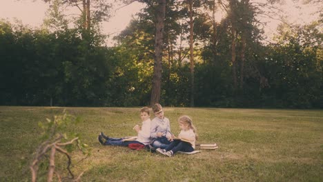 schoolboys-with-little-girl-have-lunch-on-grass-in-park