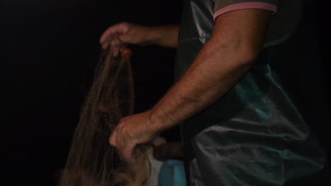 a fisherman quickly sorts his fishnet while trawling at night