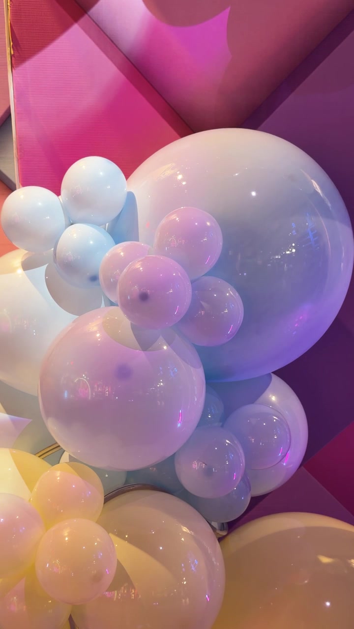 Grappolo di palloncini pastello risplende sotto luci colorate e lampeggianti a una festa al chiuso, sfondo festivo verticale per celebrazioni