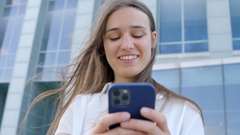 business woman texting and smiling outside office, front view