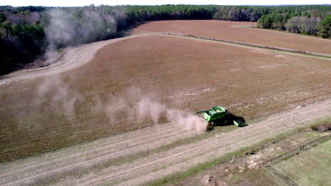 drone footage of soy bean harvesting on a farm field with a harvester or tractor, rotating aerial shot