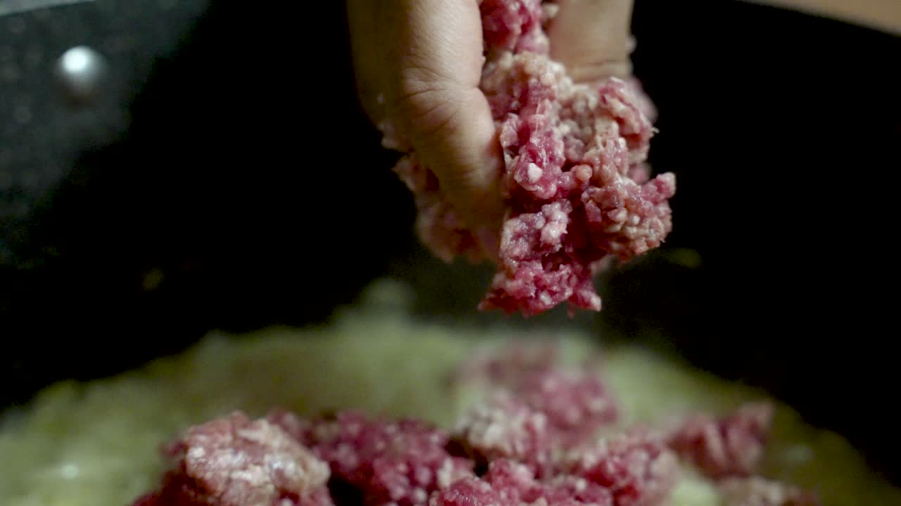 Chef adding minced beef to the pot, crafting a rich and flavorful bolognese sauce in a bustling kitchen environment