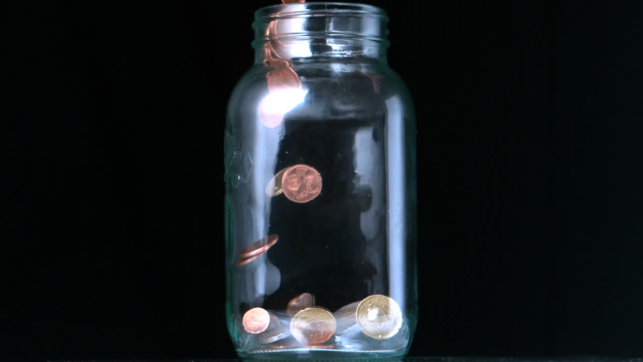 Coins pouring into glass jar