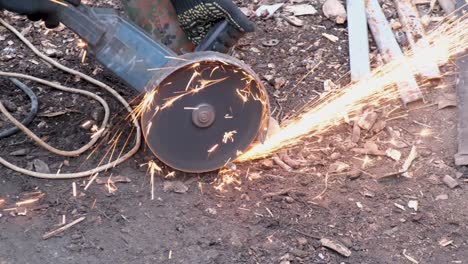 el hombre trabaja en la sierra circular. las chispas vuelan del metal caliente. el proceso de trabajo.