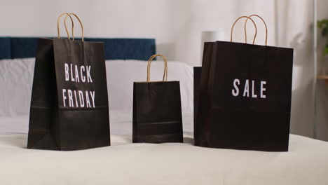 black friday shopping bags on a bed