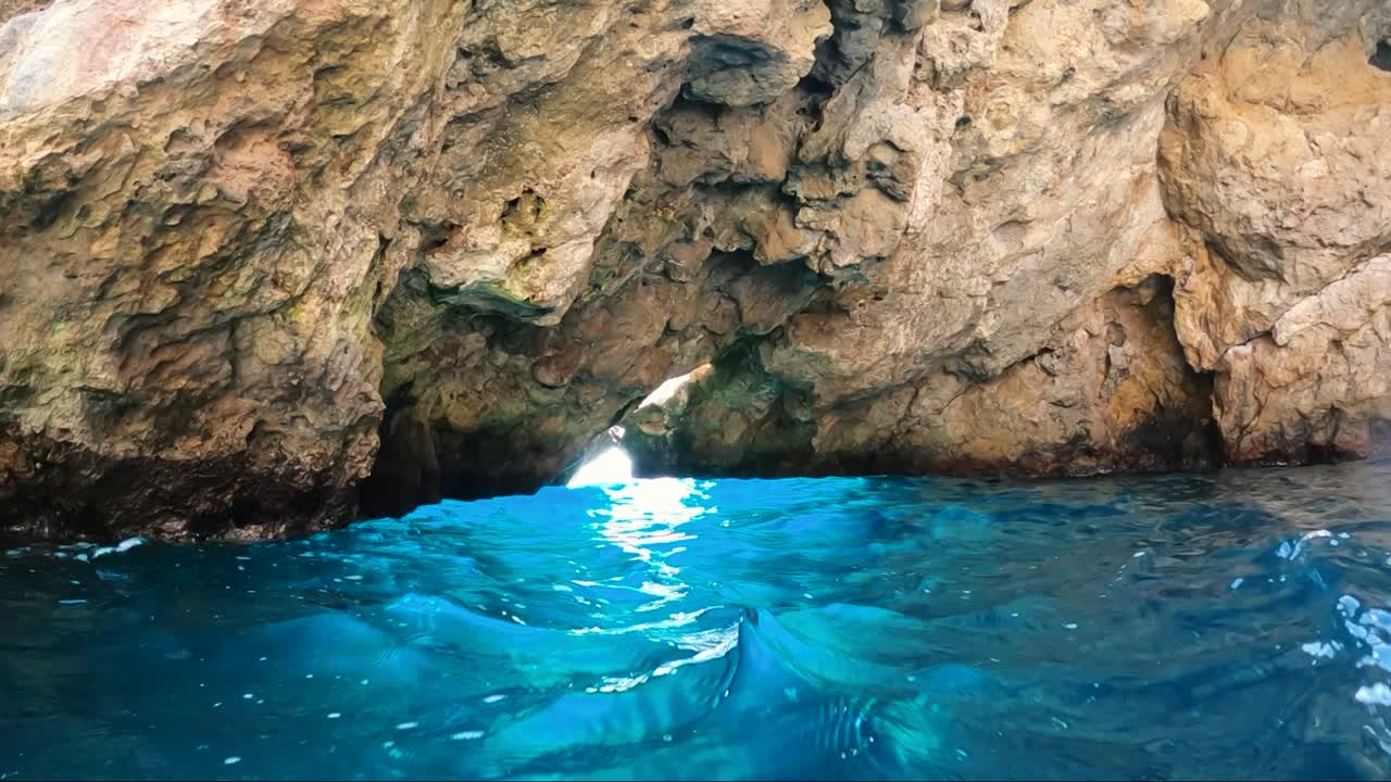 caverna sobre agua turquesa con un agujero en el que entra luz sobreexpuesta e ilumina el agua
