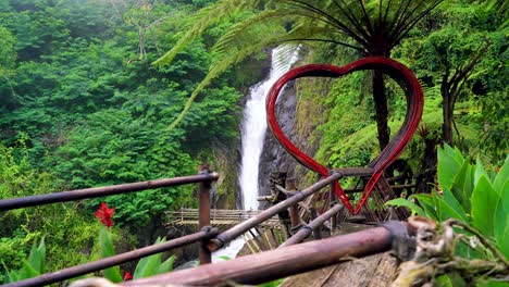 Dolly-shot-of-romantic-wooden-heart-with-epic-waterfall-in-background