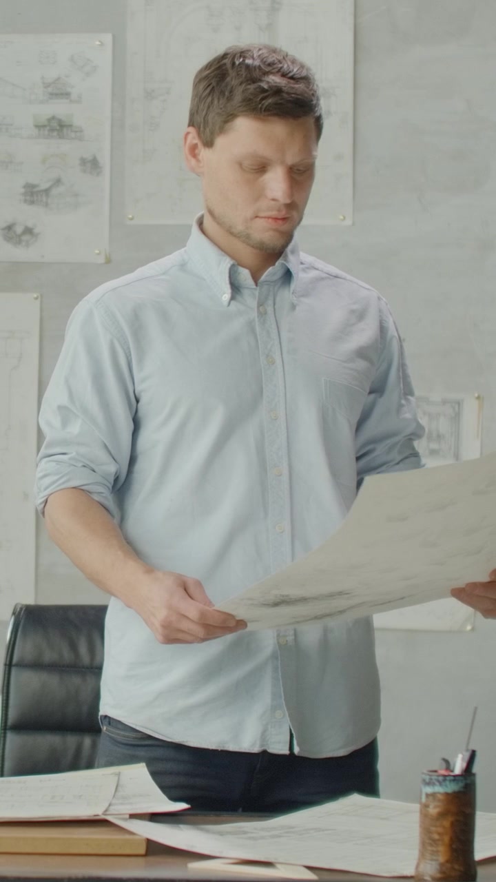Architect Reviewing Blueprints in Modern Office