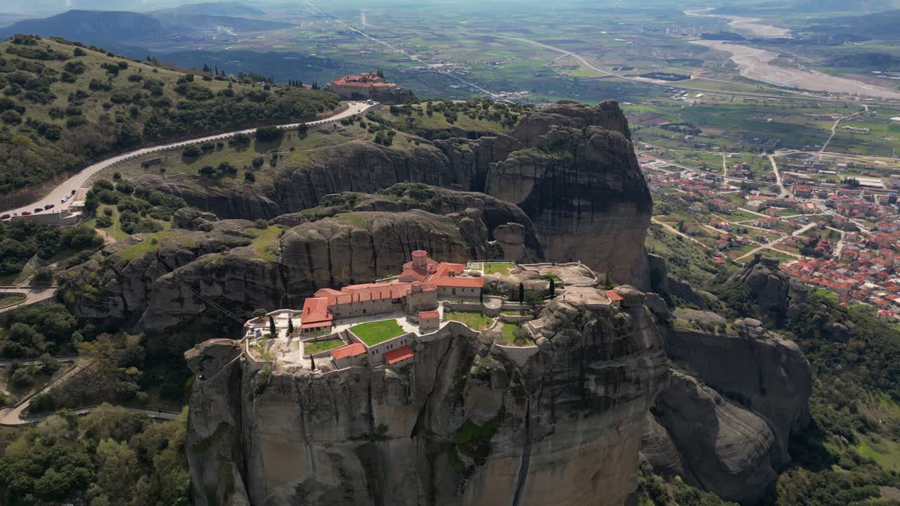 Aerial of Roussanou Monastery with red roof atop rock tower in scenic Greek region