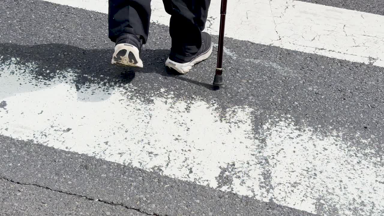 Low angle shot of a senior citizen walking across a zebra crossing in Tokyo, Japan