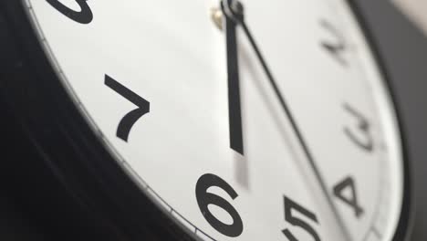 white clock face close up in time lapse on dark grey wall