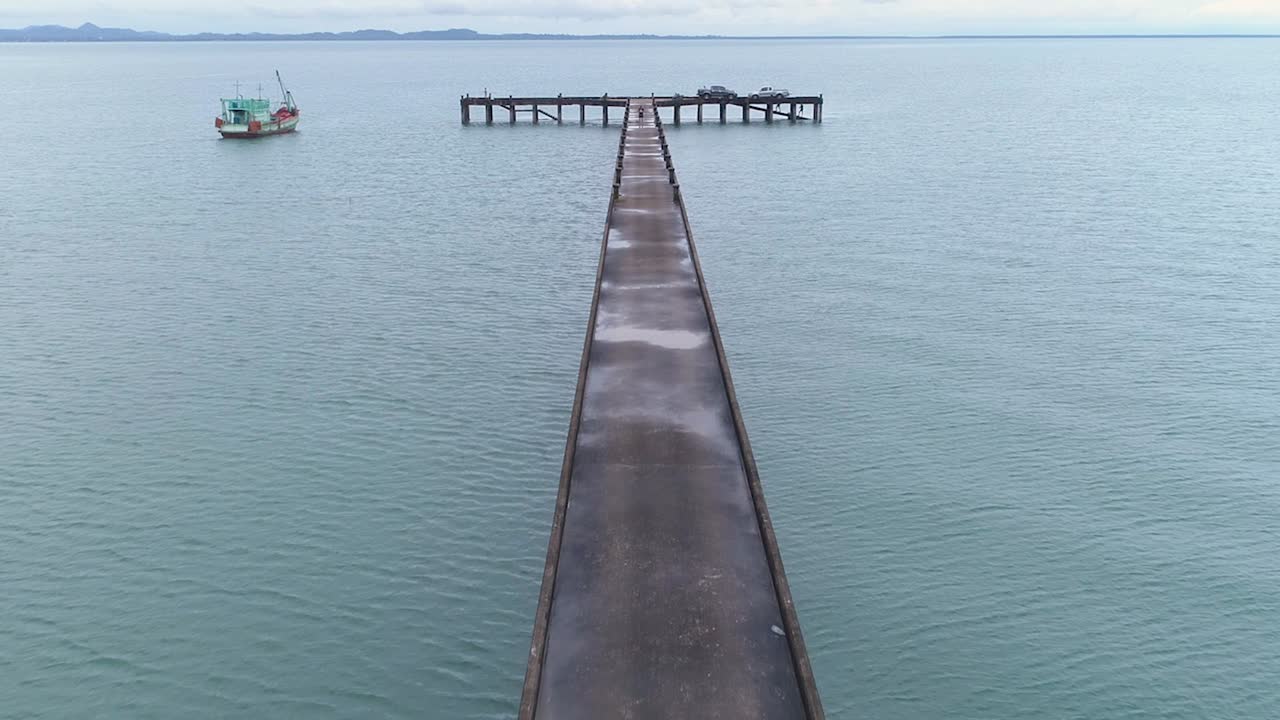 한 남자가 위를 걷고 있는 바다로 이어지는 부두의 드론 샷