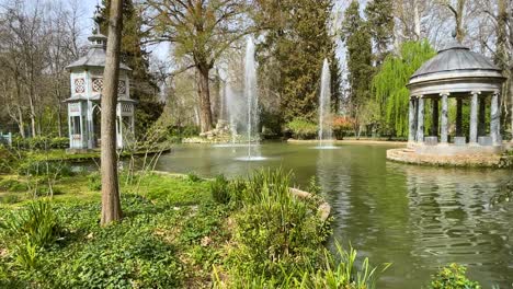 lateral filming of the pond of the prince's garden called chinesco with its blue marble temple and its striking painted bird house and lush vegetation in its surroundings on a spring morning