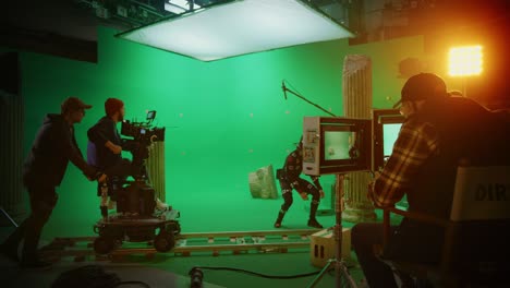 in the big film studio professional crew shooting blockbuster movie. director commands cameraman to start shooting green screen cgi scene with actor wearing motion tracking suit and head rig